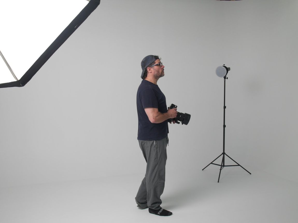 A man holding a camera in a white room