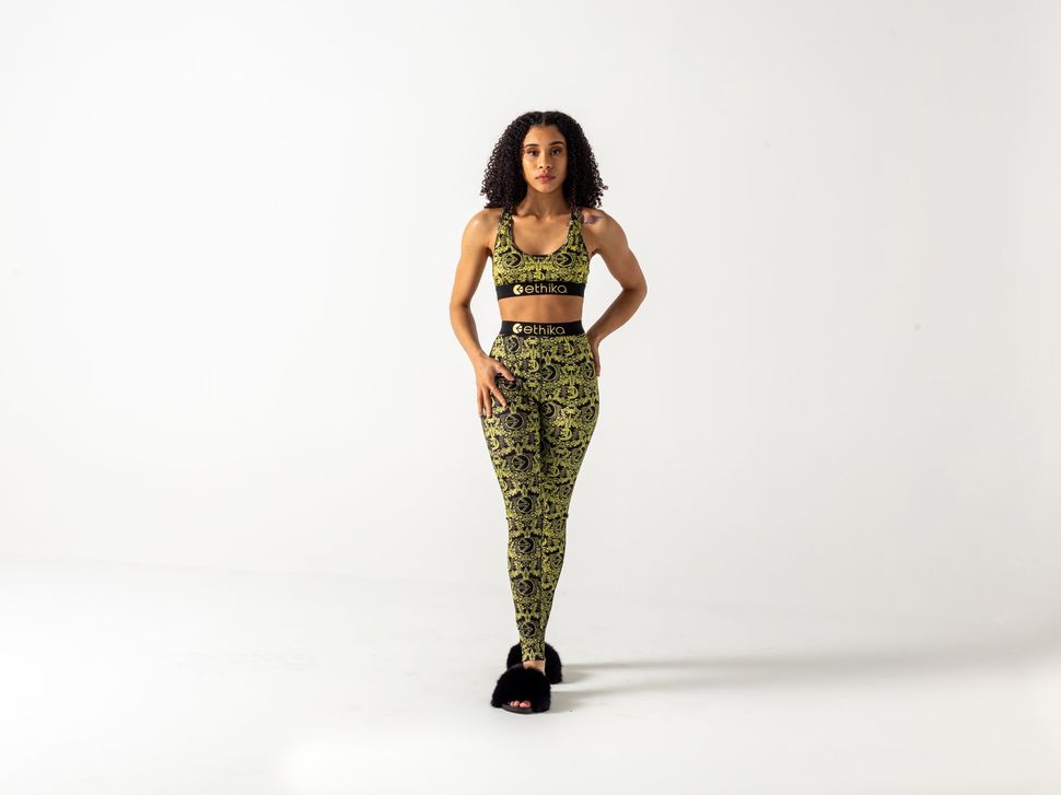 A woman in a crop top and leggings is standing on a white background.