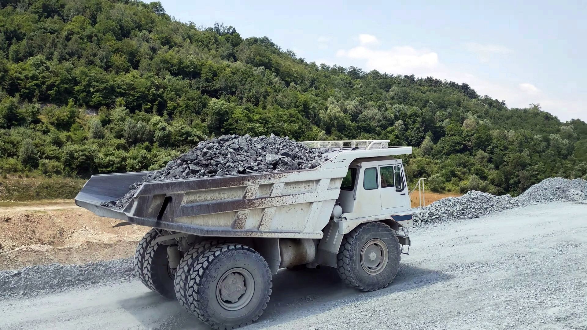 A dump truck is driving down a gravel road.