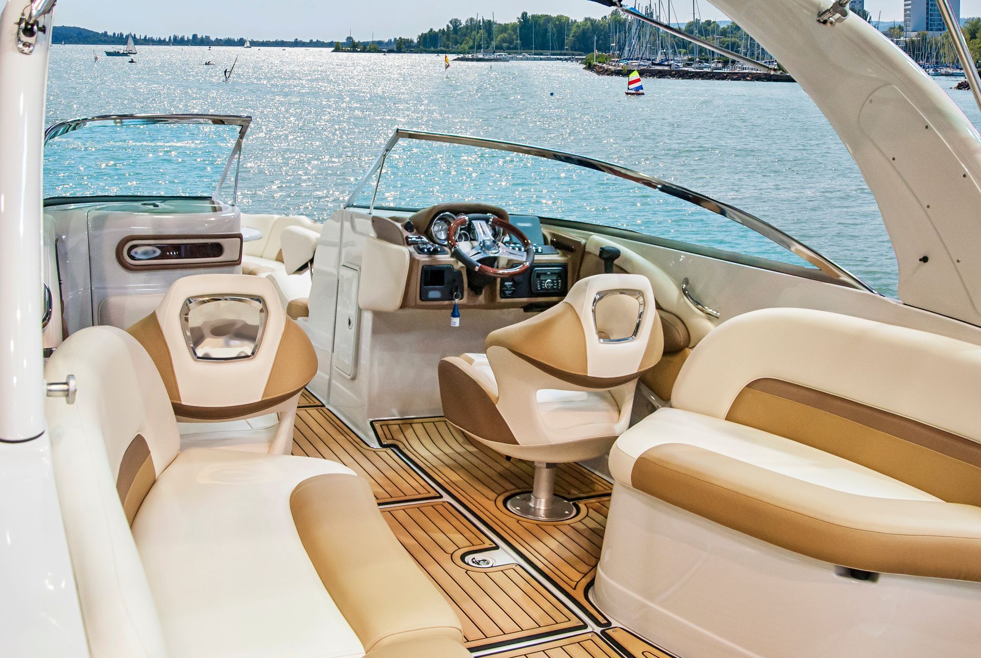 The inside of a boat with a wooden deck and a steering wheel.