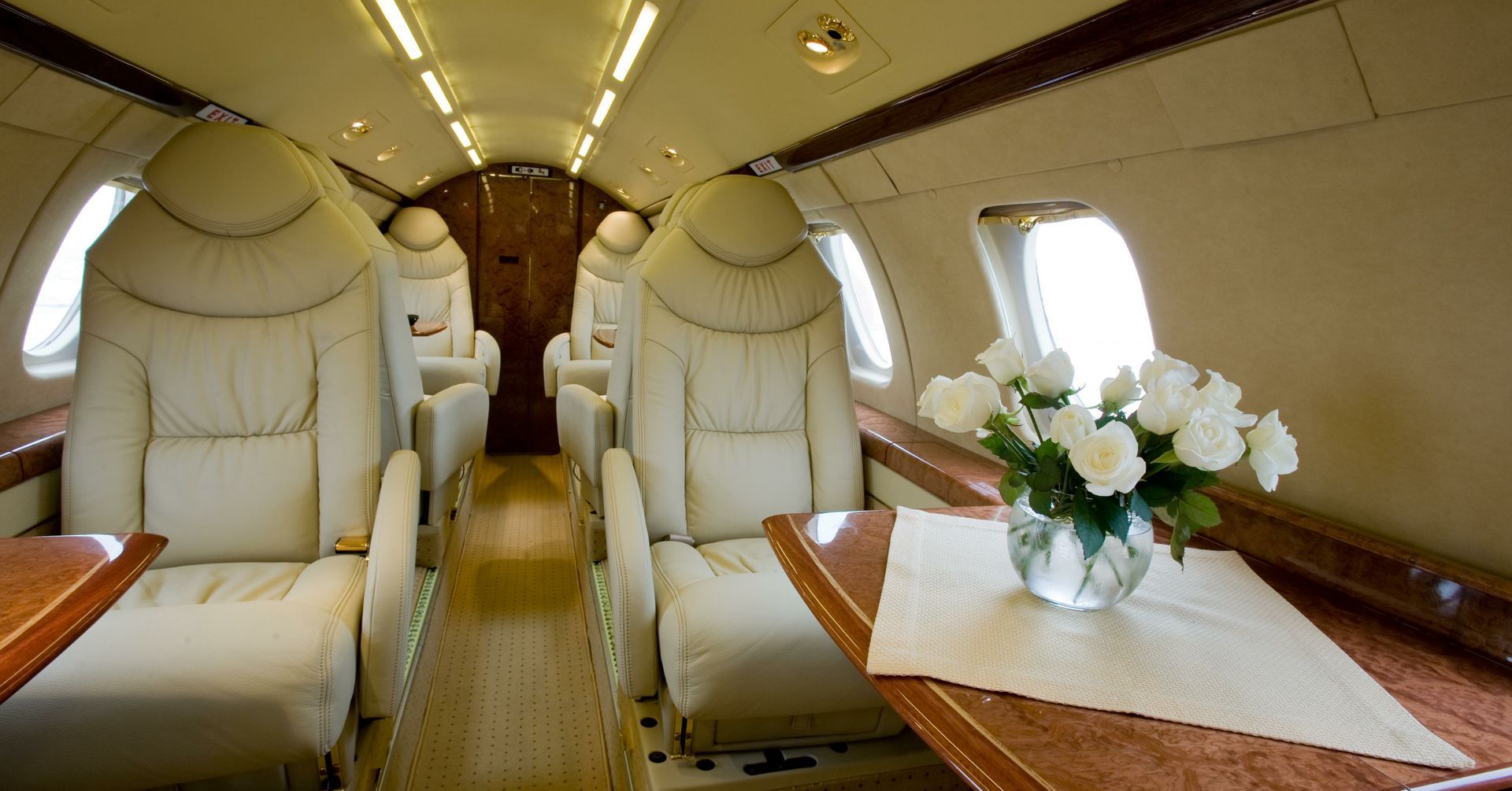 The inside of a private jet with a vase of flowers on the table.