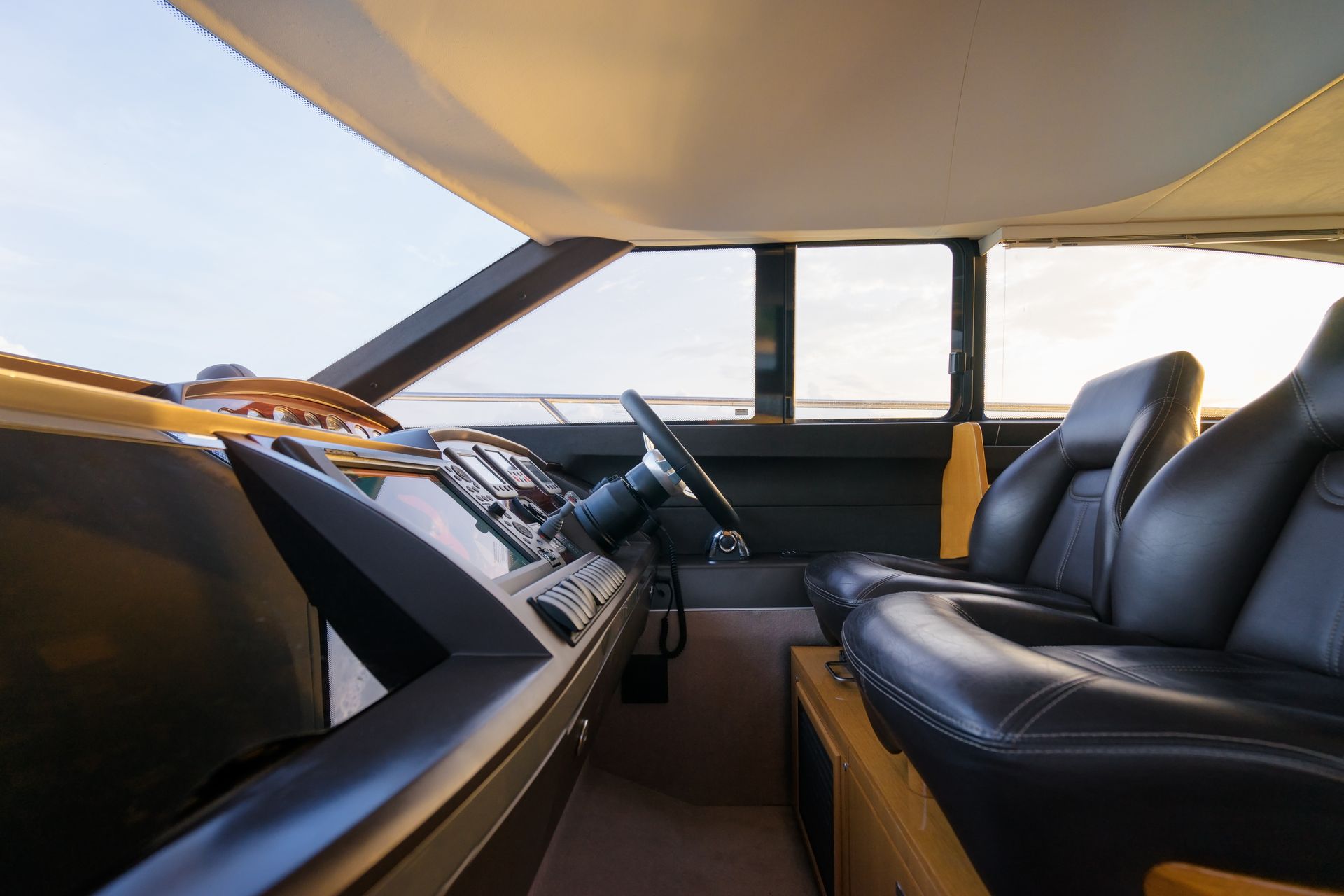 The interior of a yacht with black leather seats and a steering wheel.