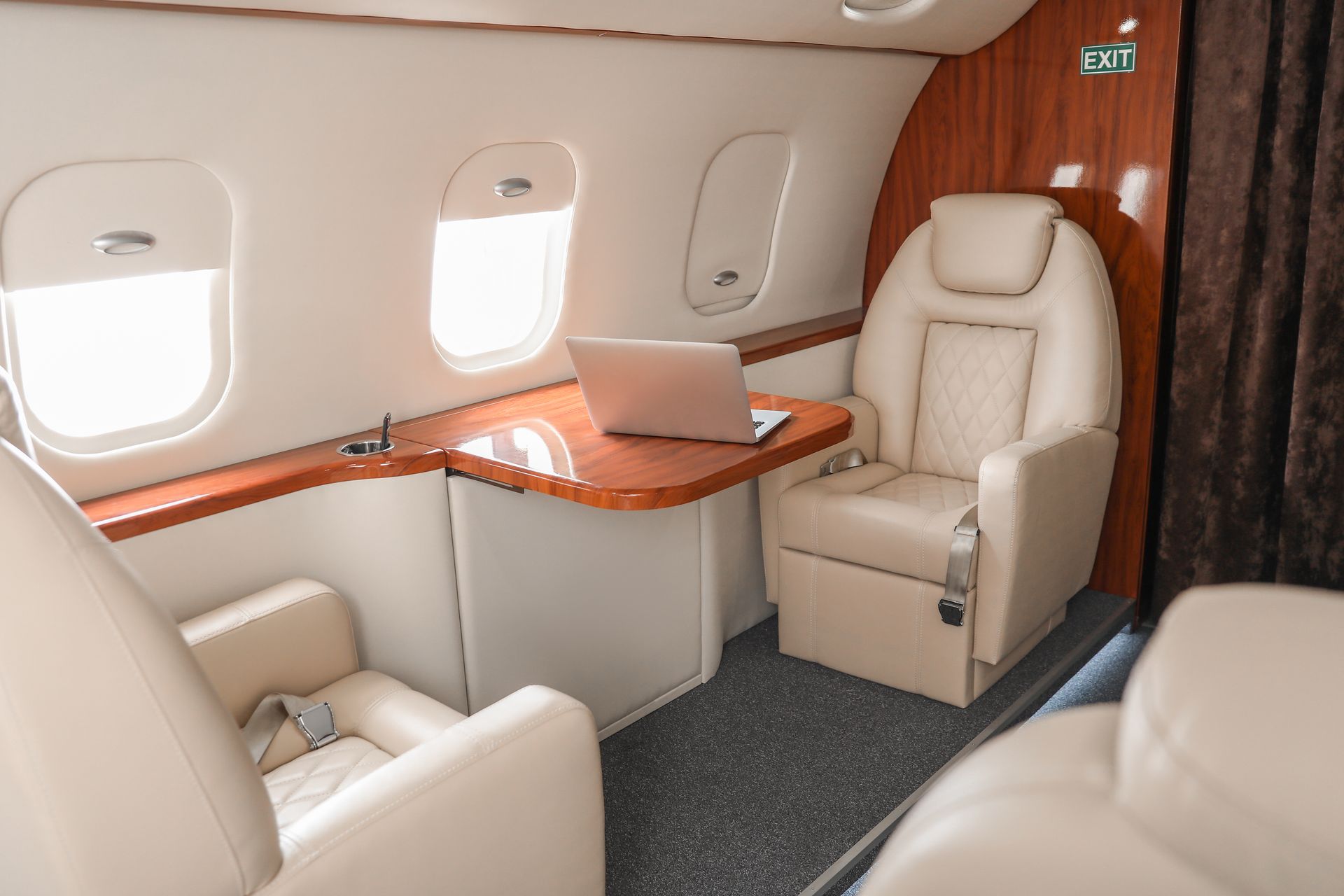 The inside of a private jet with a laptop on a table.