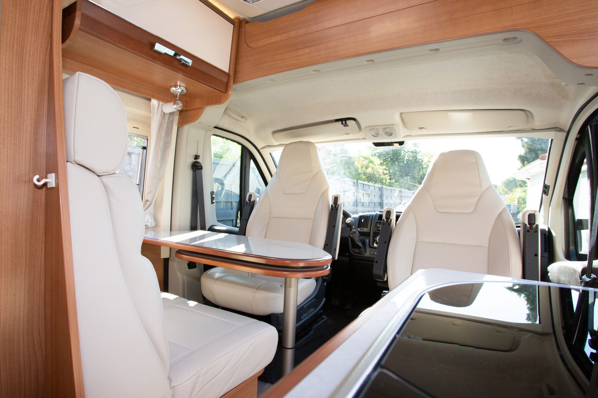The inside of a camper van with white seats and a table.