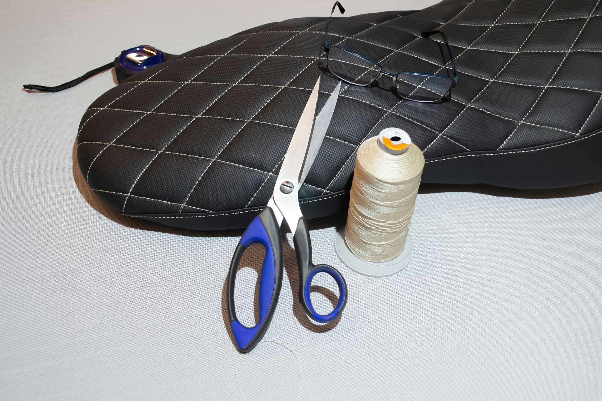 A pair of scissors sitting next to a spool of thread