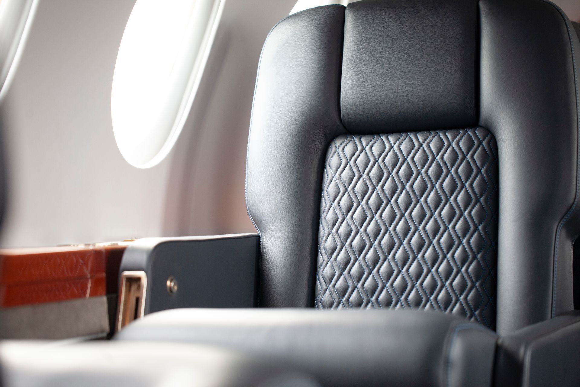 A close up of a black leather seat on an airplane