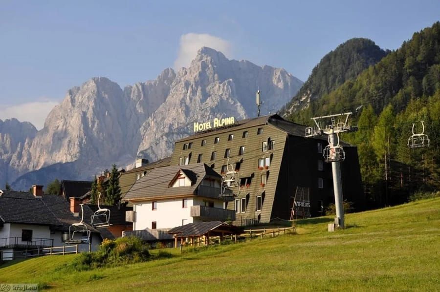Mountain lodge and ski lift in a grassy alpine village beneath rocky peaks