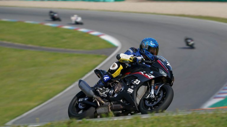 Motorcycle racer in blue helmet leans into a turn on a racetrack