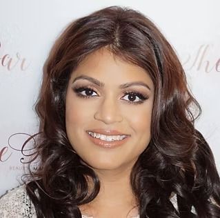 A woman with long brown hair is smiling for the camera