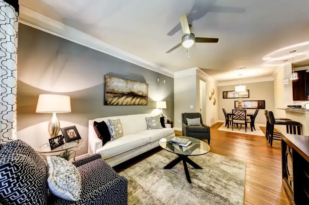 a living room with a couch , chairs , a coffee table and a ceiling fan .