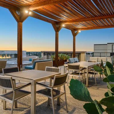 a patio with tables and chairs under a wooden canopy .
