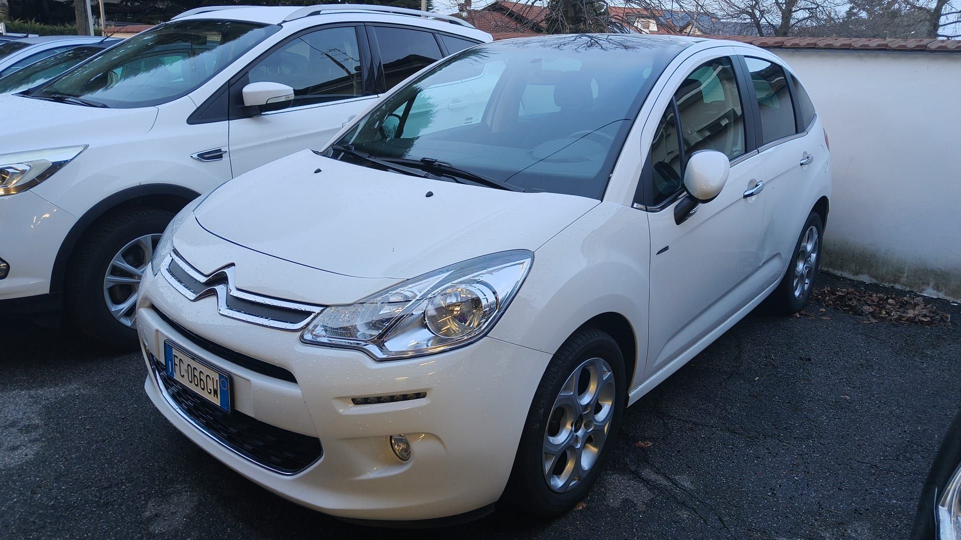 Un'auto bianca Citroen C3 parcheggiata su un piazzale asfaltato, accanto a un'altra auto.