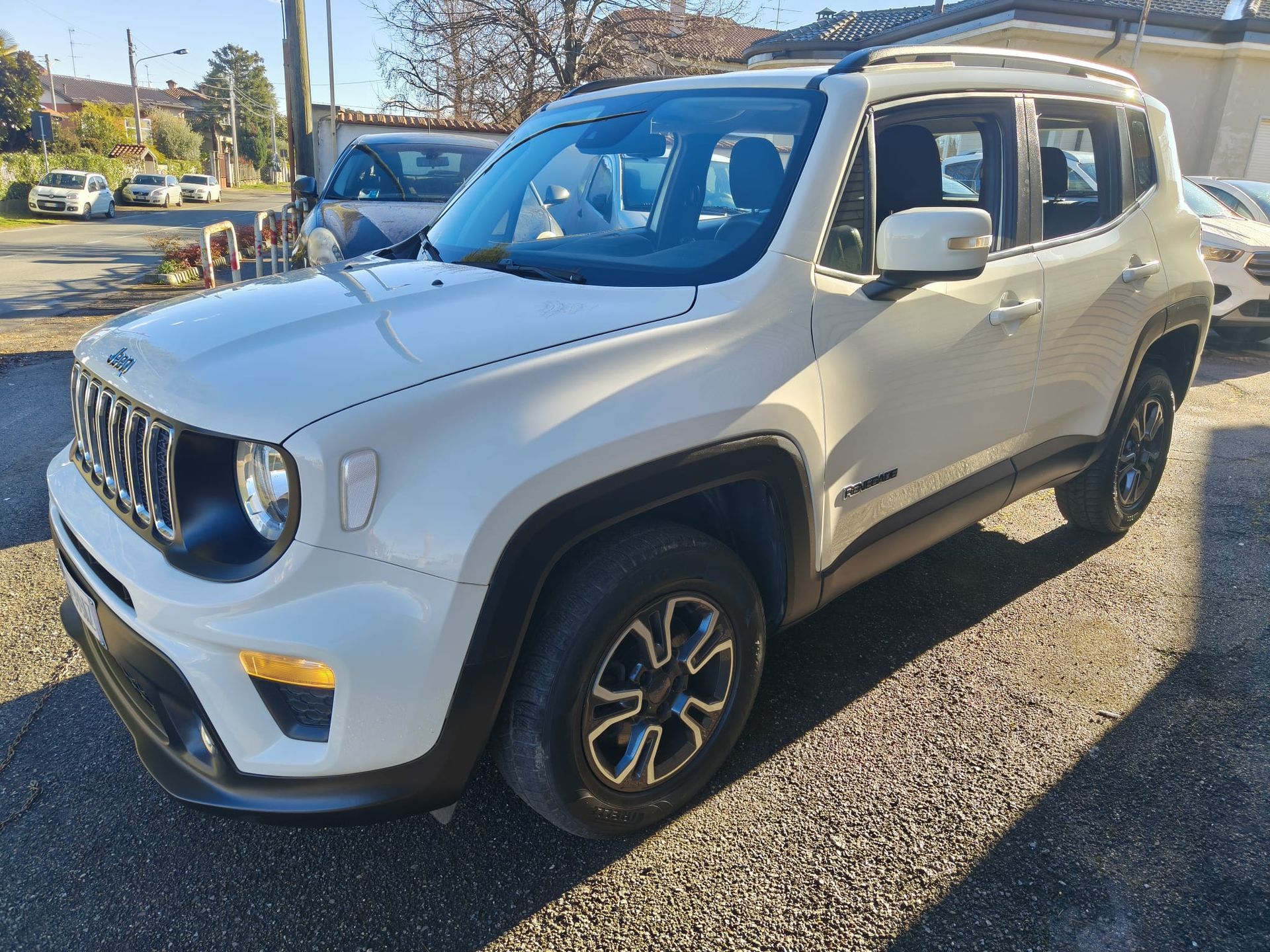 Jeep Renegade bianca parcheggiata su una superficie ghiaiosa.