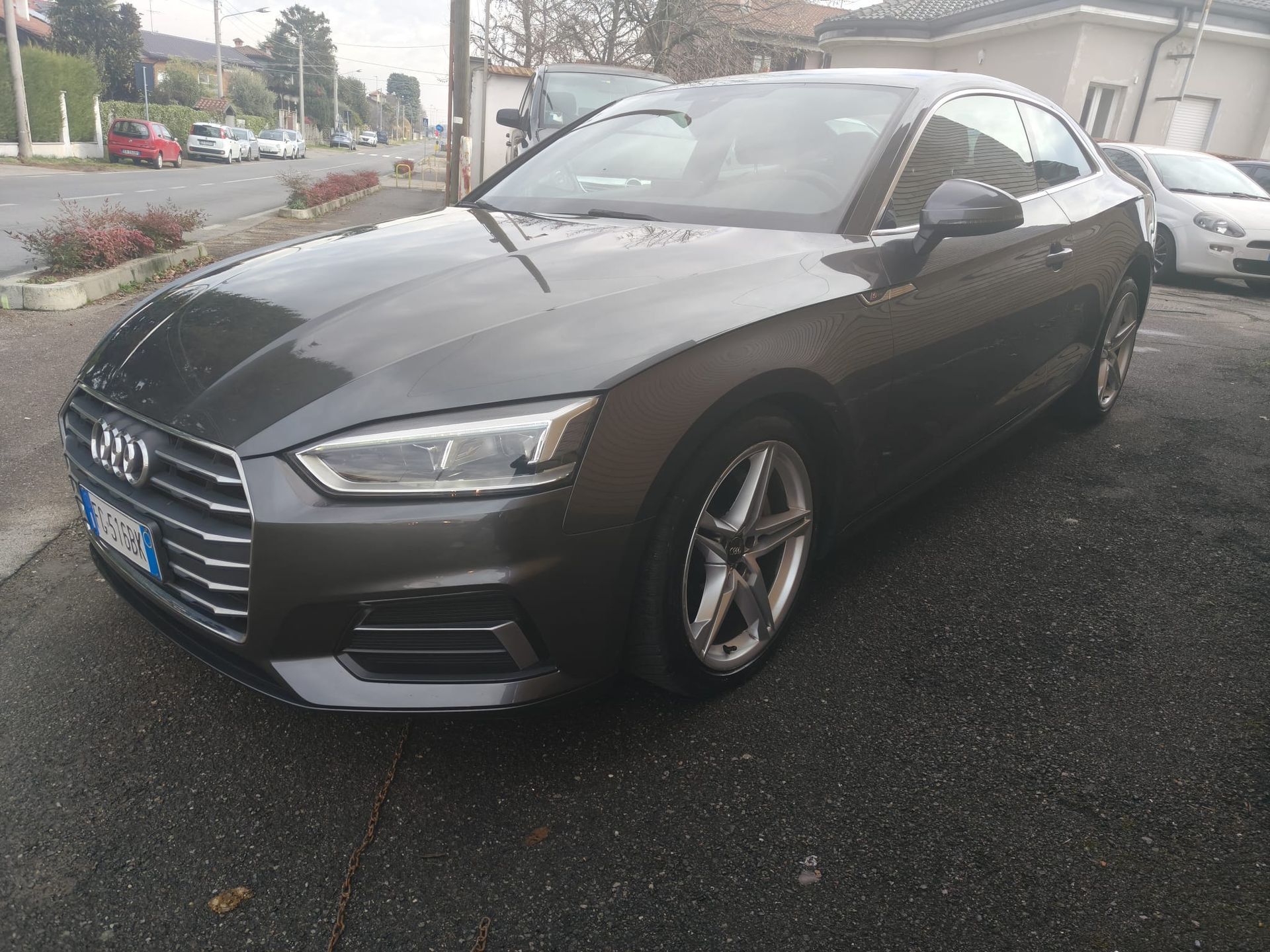 Audi coupé grigio scuro parcheggiata su una strada asfaltata.