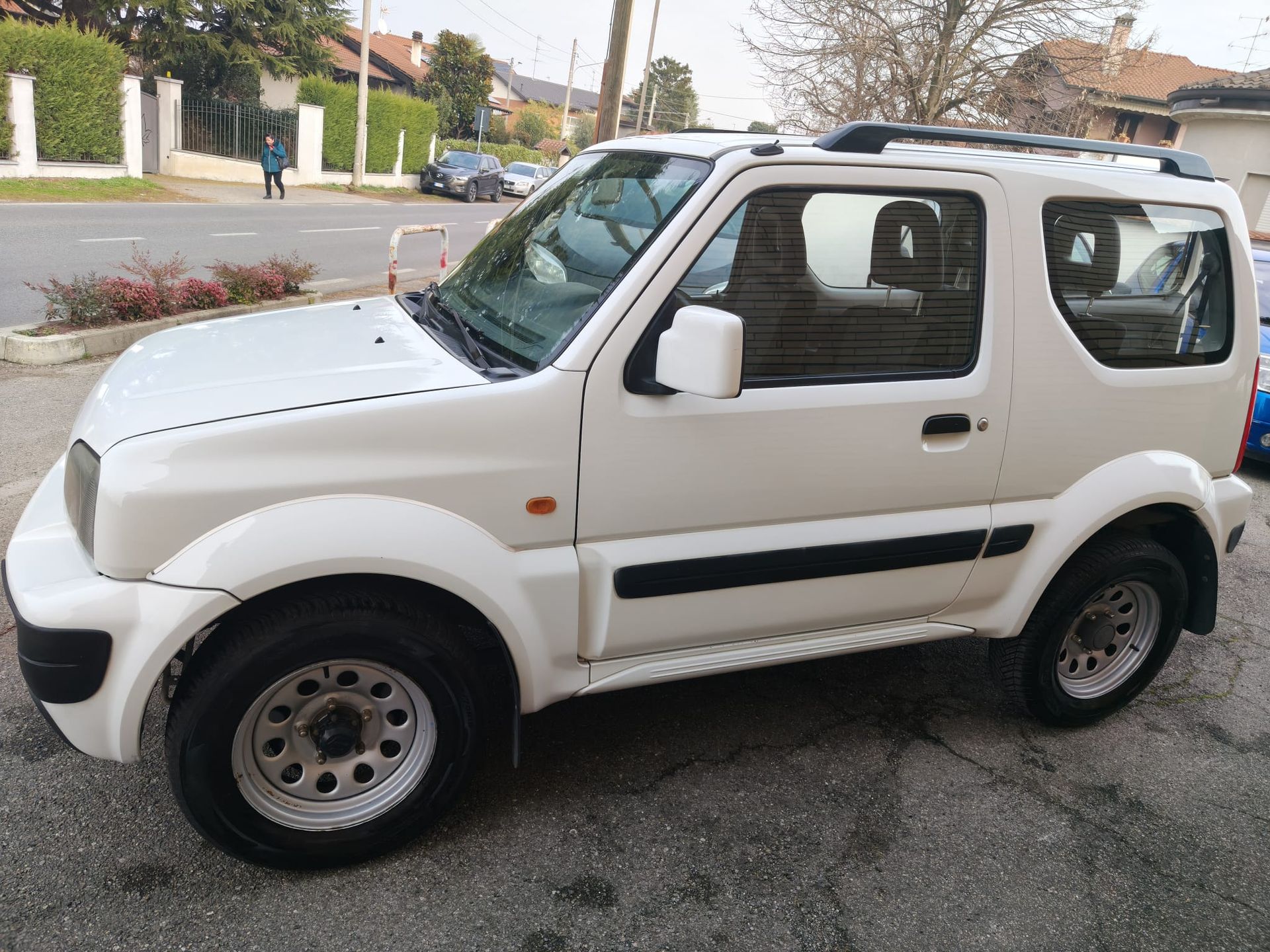 Un SUV Suzuki Jimny bianco parcheggiato su una strada cittadina.