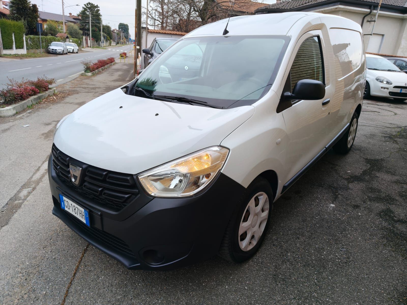 Furgone Dacia Dokker bianco parcheggiato su una strada con paraurti e griglia neri.
