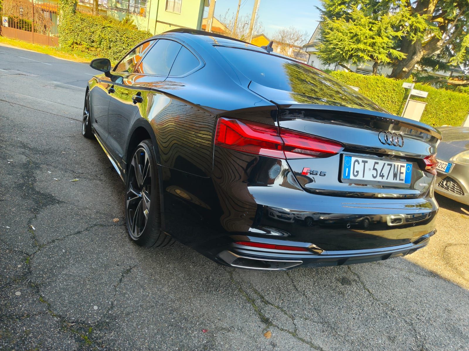 Audi RS5 coupé nera parcheggiata su un vialetto asfaltato con targa italiana.