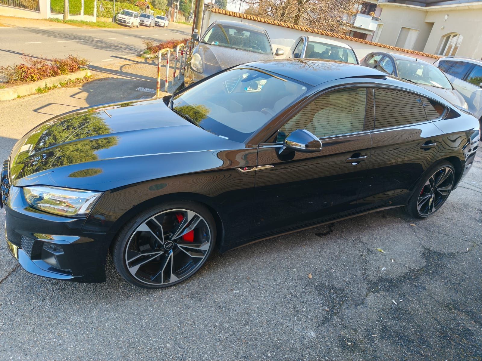 Audi coupé nera con pinze dei freni rosse parcheggiata sul marciapiede.