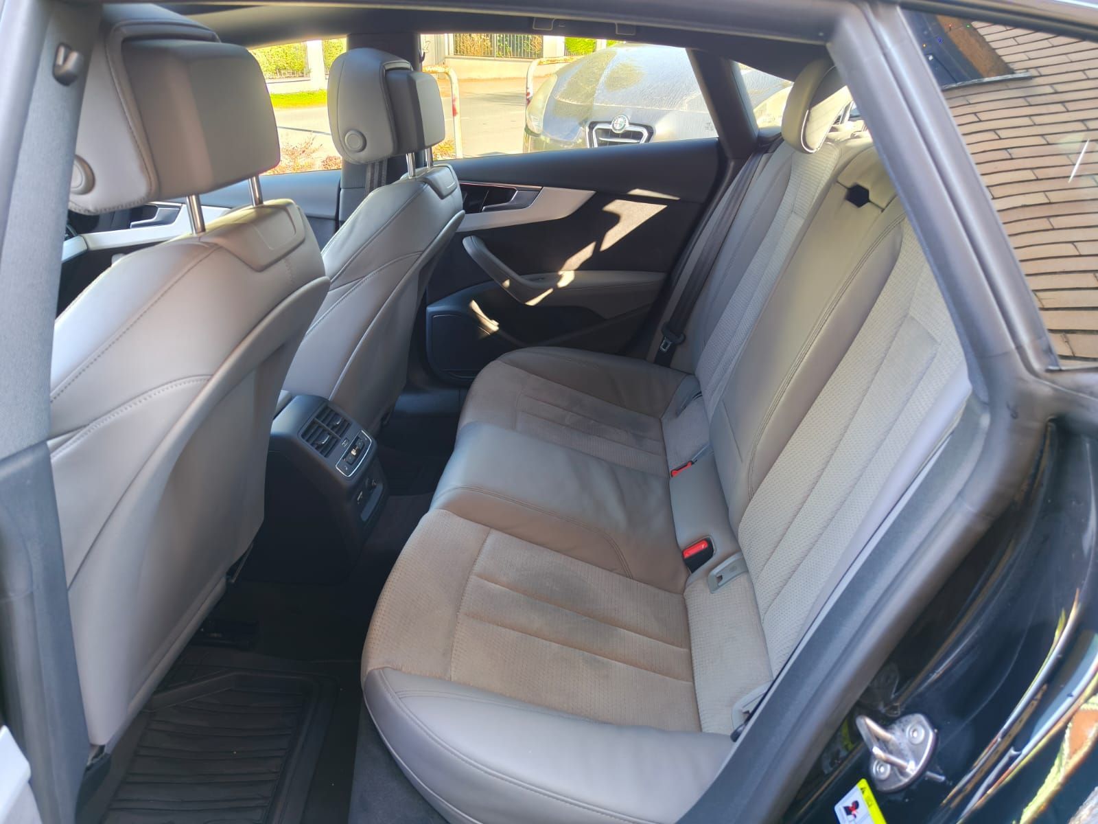 Vista interna dei sedili posteriori di un'auto grigia; sedili in pelle chiara.