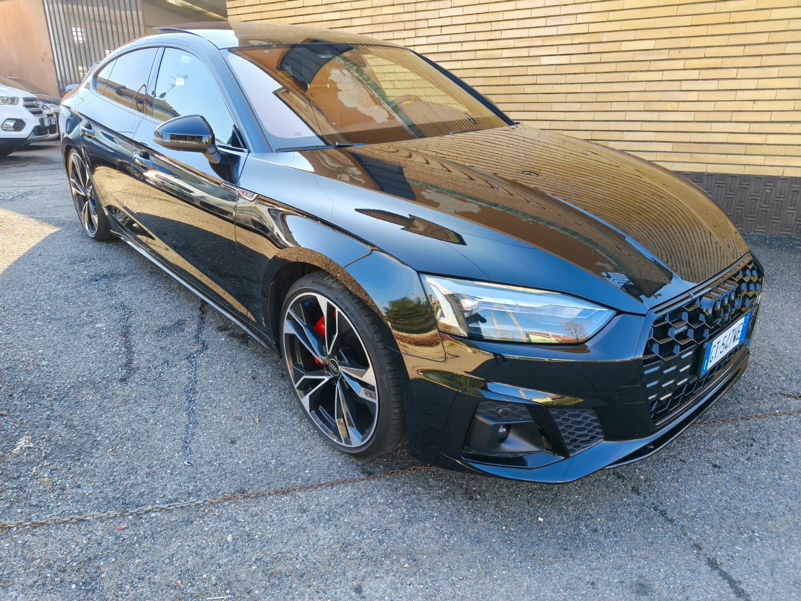 Audi coupé nera parcheggiata sull'asfalto. Griglia nera, pinze dei freni rosse.