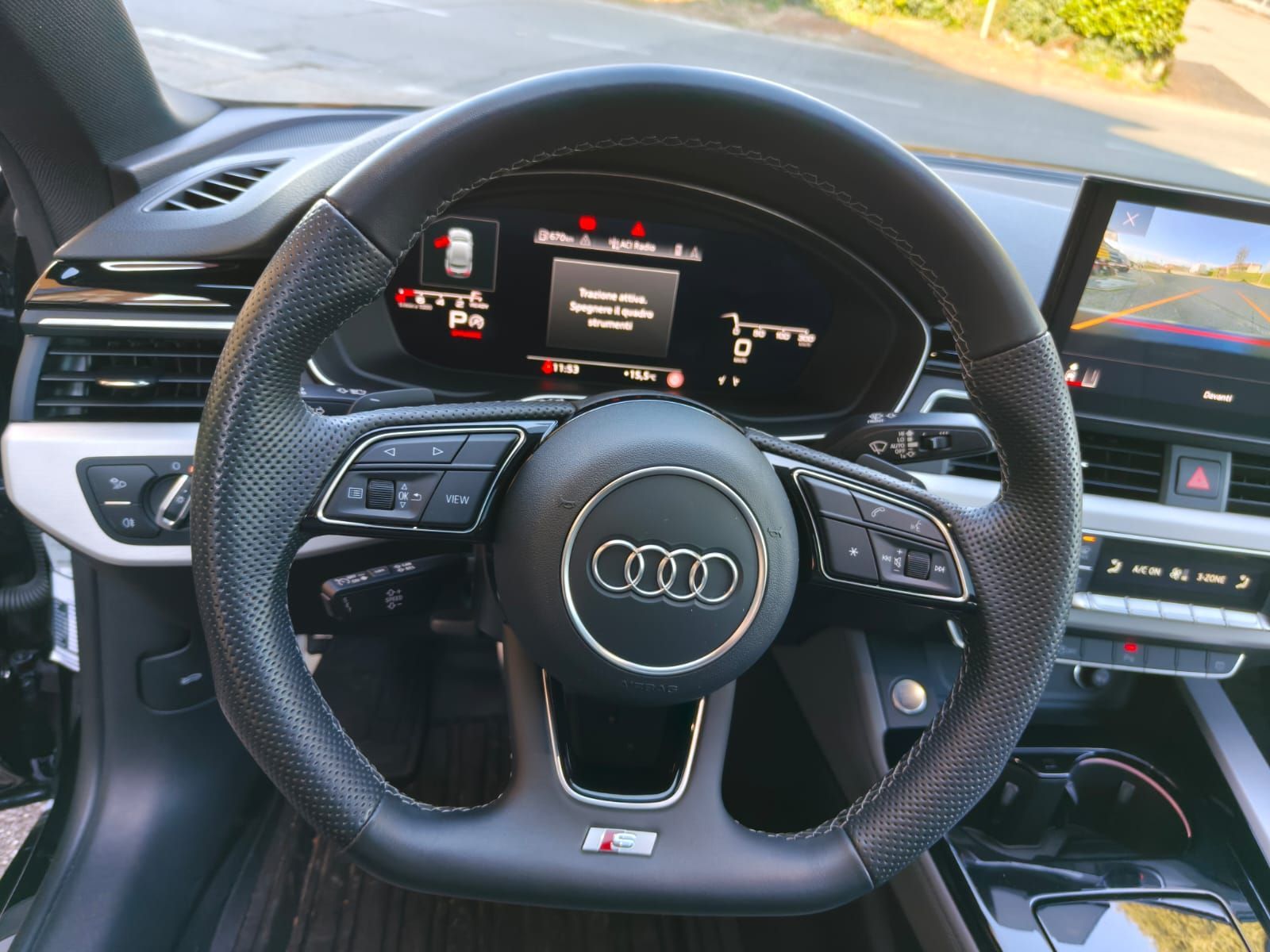 Volante Audi nero con comandi e display sul cruscotto.