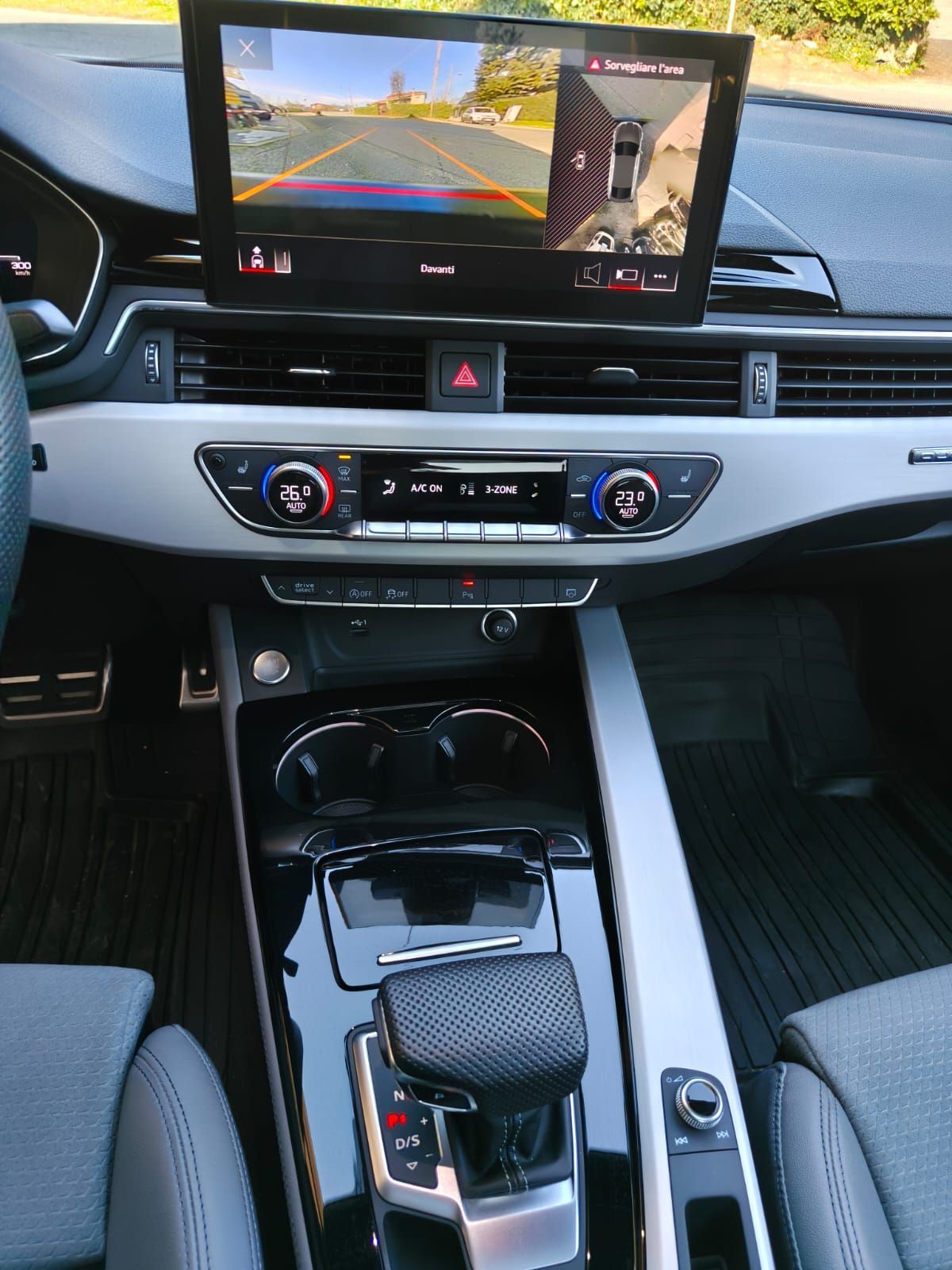 Interno di un'auto moderna che mostra il cruscotto, lo schermo dell'infotainment, il cambio e la console centrale.