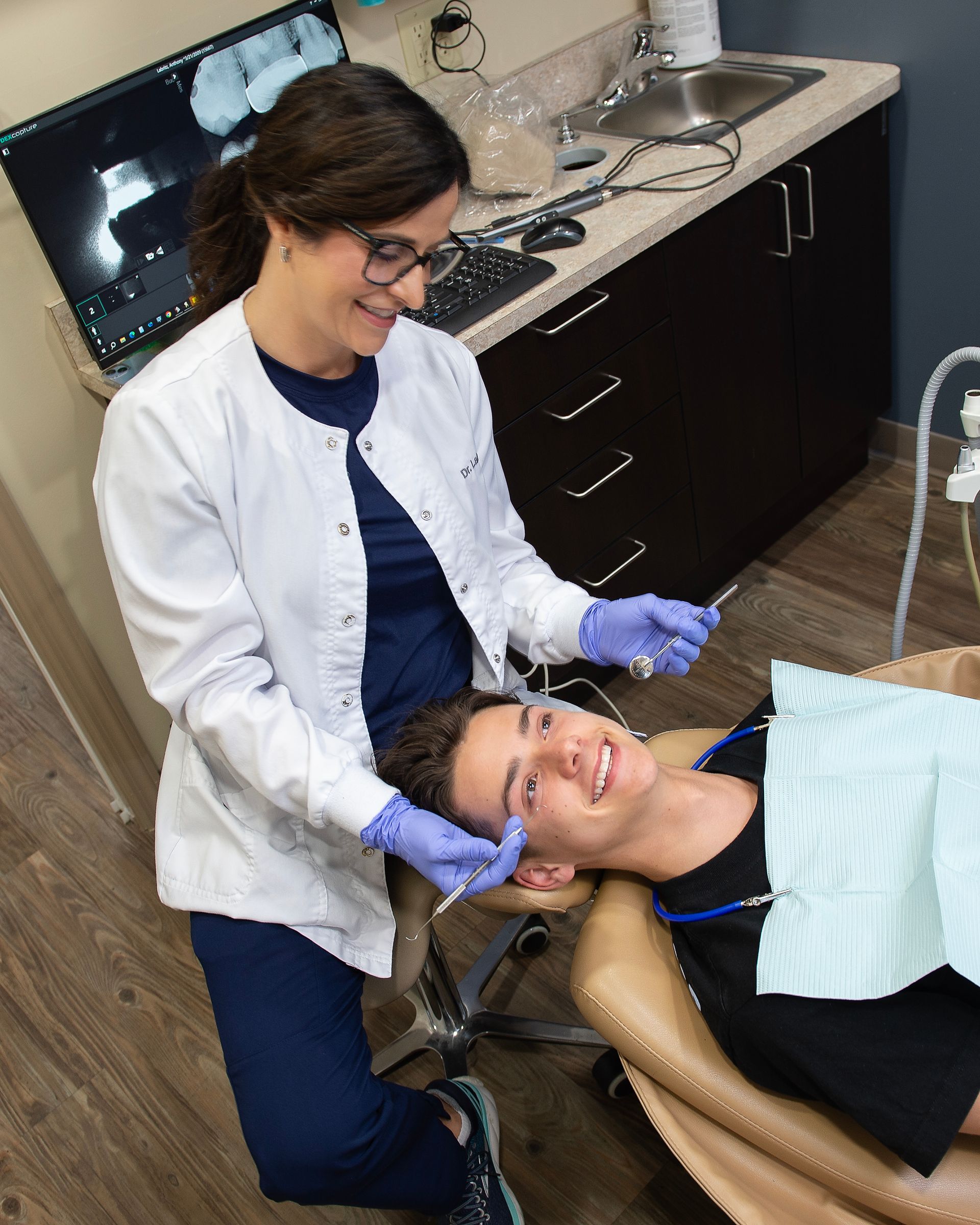 A dentist is examining a patient 's teeth in a dental office.