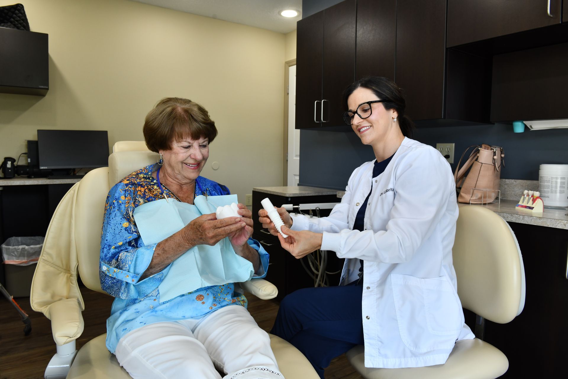 A woman is sitting in a dental chair talking to a dentist.
