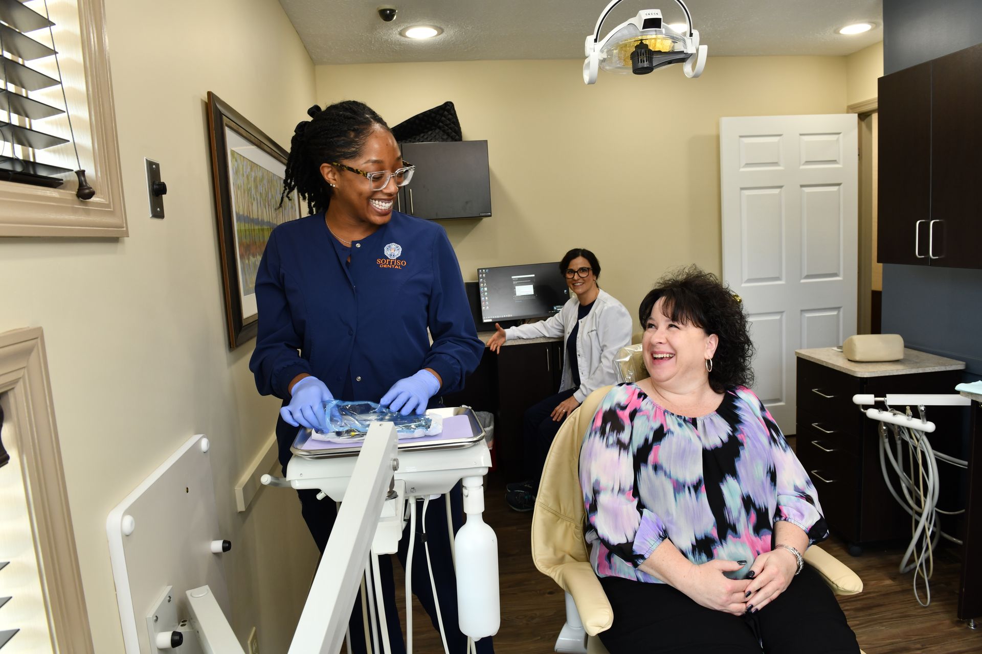 A woman is sitting in a dental chair talking to a dentist.