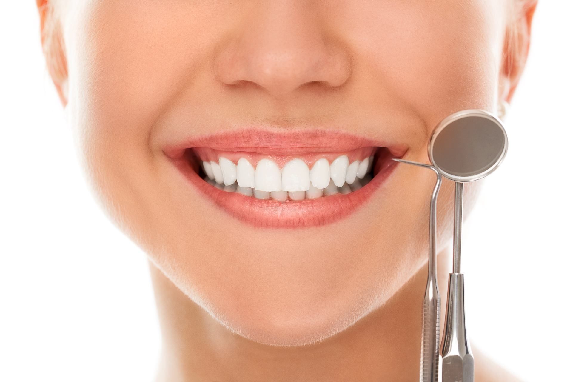 Woman with perfect teeth smiling next to dental tools | Whole Body Health