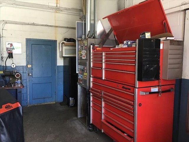 A red toolbox is sitting in a garage next to a blue door.
