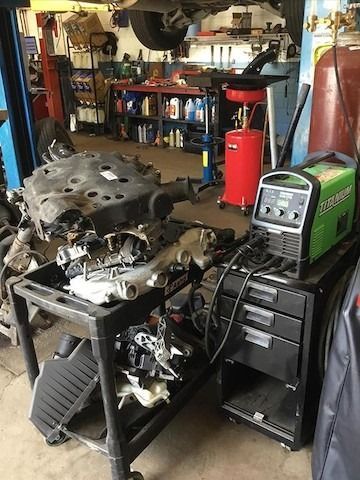 A car engine is sitting on top of a cart in a garage.