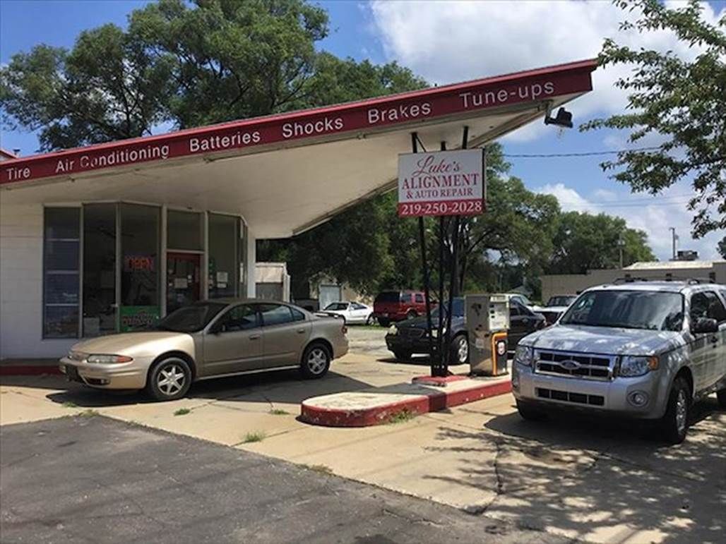 Two cars are parked in front of a car dealership.