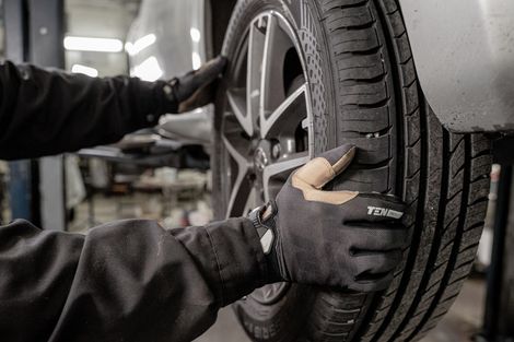 A person is changing a tire on a car in a garage.