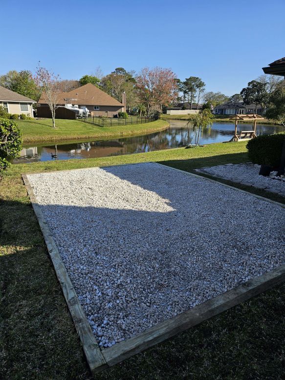 A gravel driveway leading to a lake with houses in the background.
