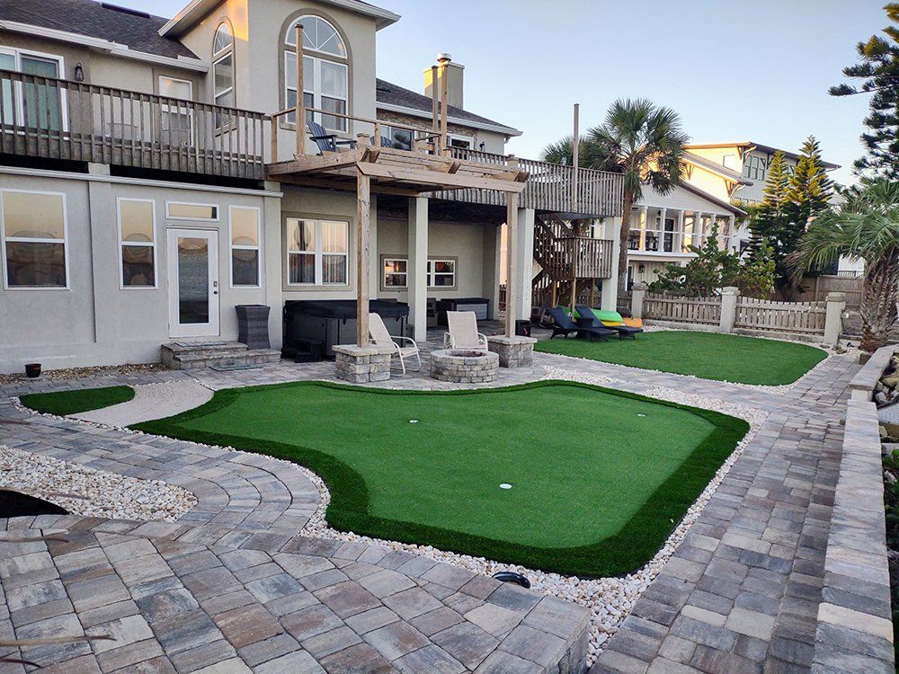 A large house with a putting green in front of it.