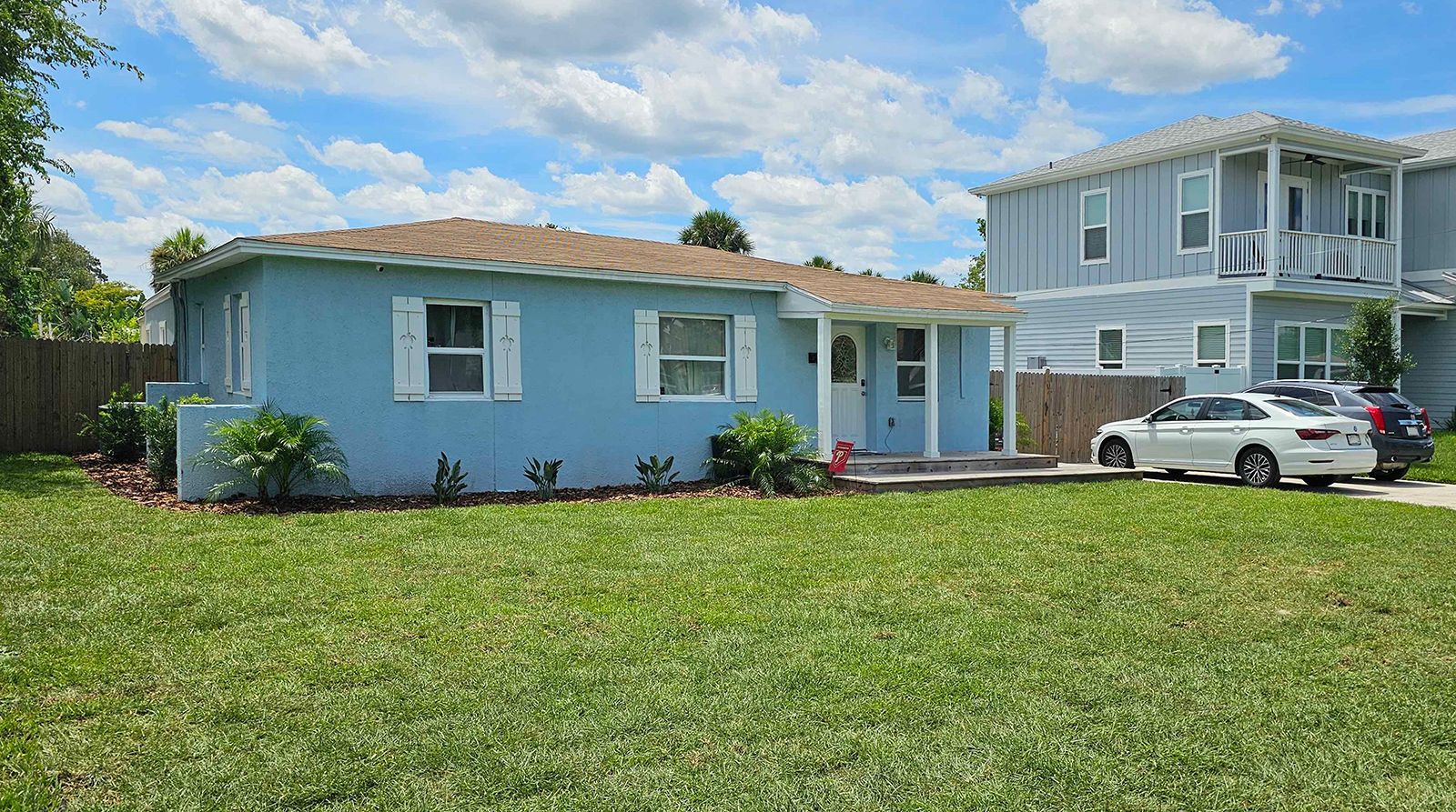 A blue house with a white car parked in front of it.