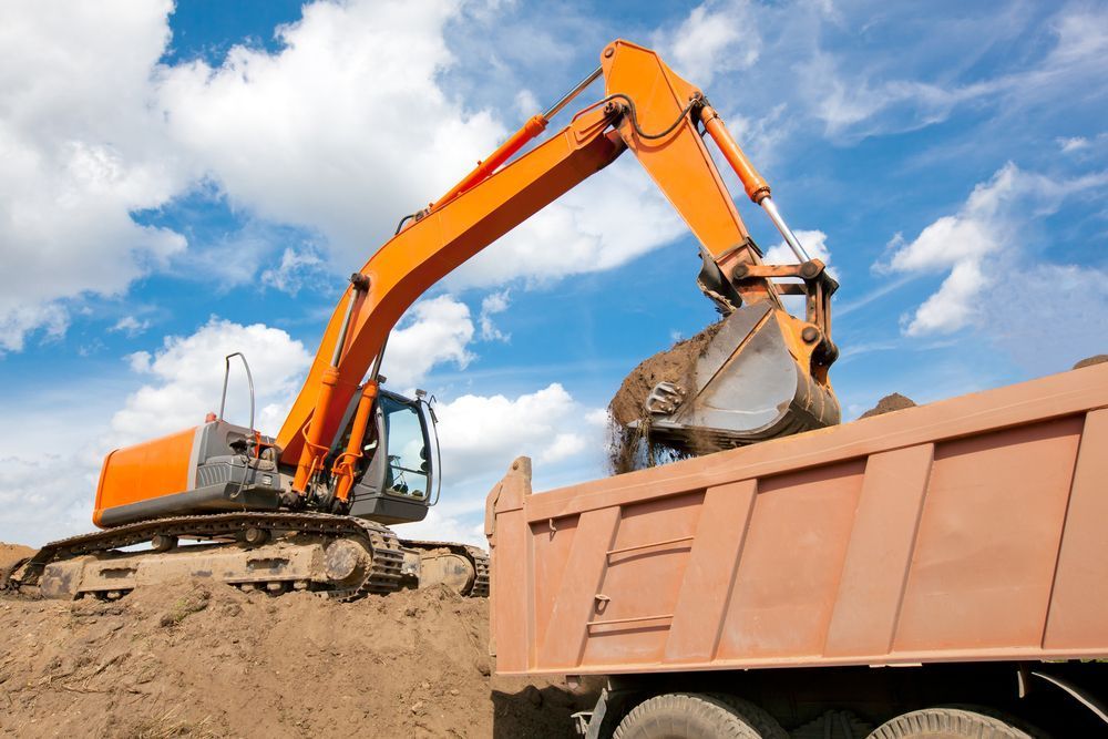 An Excavator Is Loading Dirt Into a Dump Truck — Lifestyle Demolition In Brunswick Heads, NSW