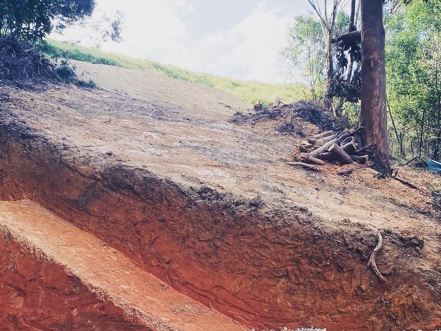 An Excavator Loading A White Dump Truck With Red Soil On A Sunny Day  — Lifestyle Demolition In Evans Head, NSW