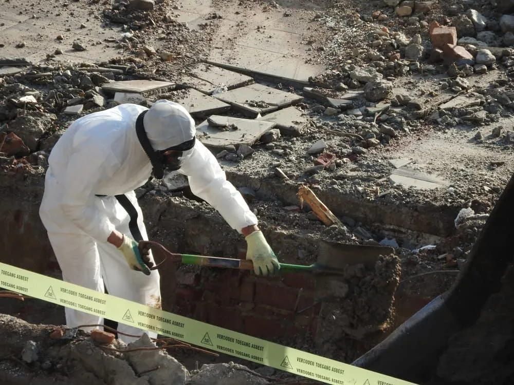 A Man in A Protective Suit Is Digging in The Dirt — Lifestyle Demolition In Mullumbimby, NSW
