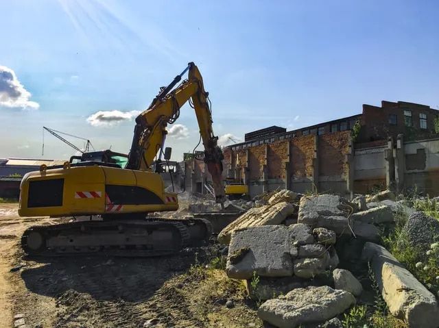 A Large Yellow Excavator Is Destroying a Building on A Construction Site — Lifestyle Demolition In Evans Head, NSW