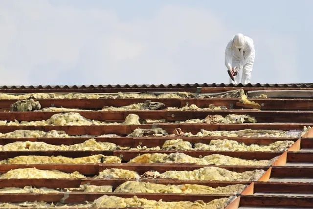 A Man in A White Suit Is Working on The Roof of A Building —Lifestyle Demolition In Evans Head, NSW