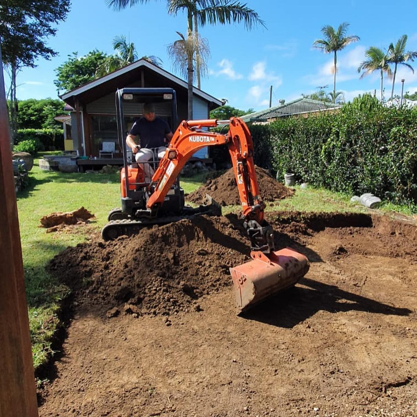Man Operating An Excavator, Digging In A Grassy Backyard — Lifestyle Demolition In Tweed Heads, NSW