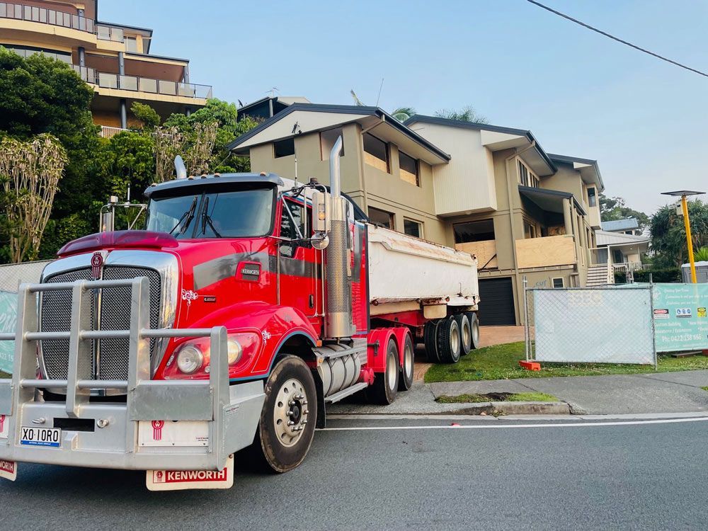 A Yellow Excavator Is Loading Concrete Into a Dumpster — Lifestyle Demolition in Kingscliff, NSW 