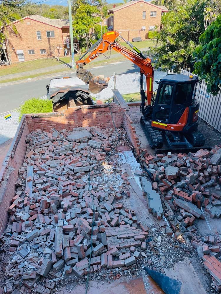 An Excavator Is Loading Bricks Into a Truck — Lifestyle Demolition in Kingscliff, NSW
