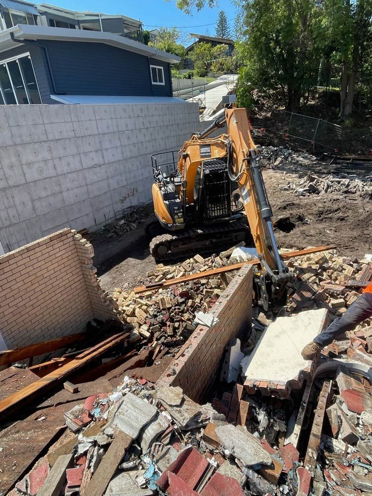 A Large Yellow Excavator Is Demolishing a Building — Lifestyle Demolition in Kingscliff, NSW