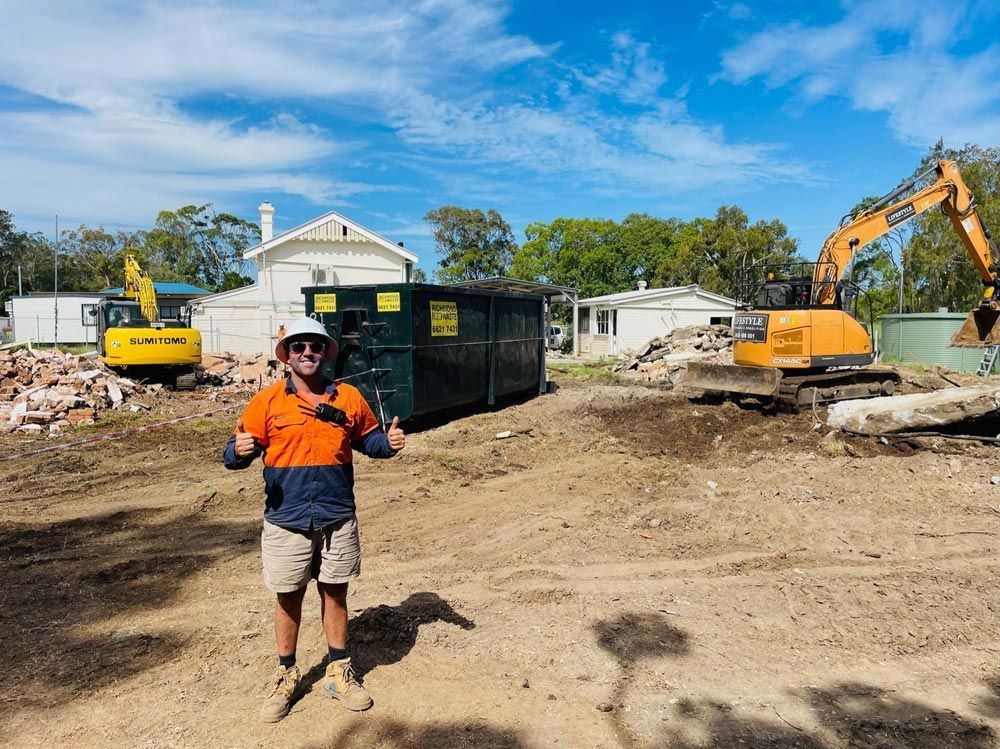 A Large Yellow Excavator Is Sitting on Top of A Dirt Field — Lifestyle Demolition in Kingscliff, NSW