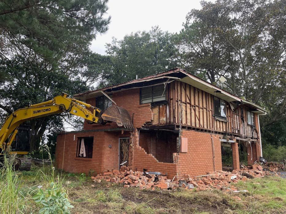 A Brick House Is Being Demolished by A Yellow Excavator — Lifestyle Demolition in Kingscliff, NSW