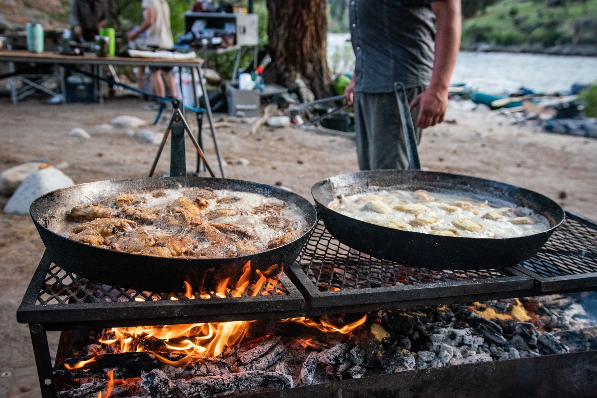 Two pans of food are cooking on a grill over a fire.