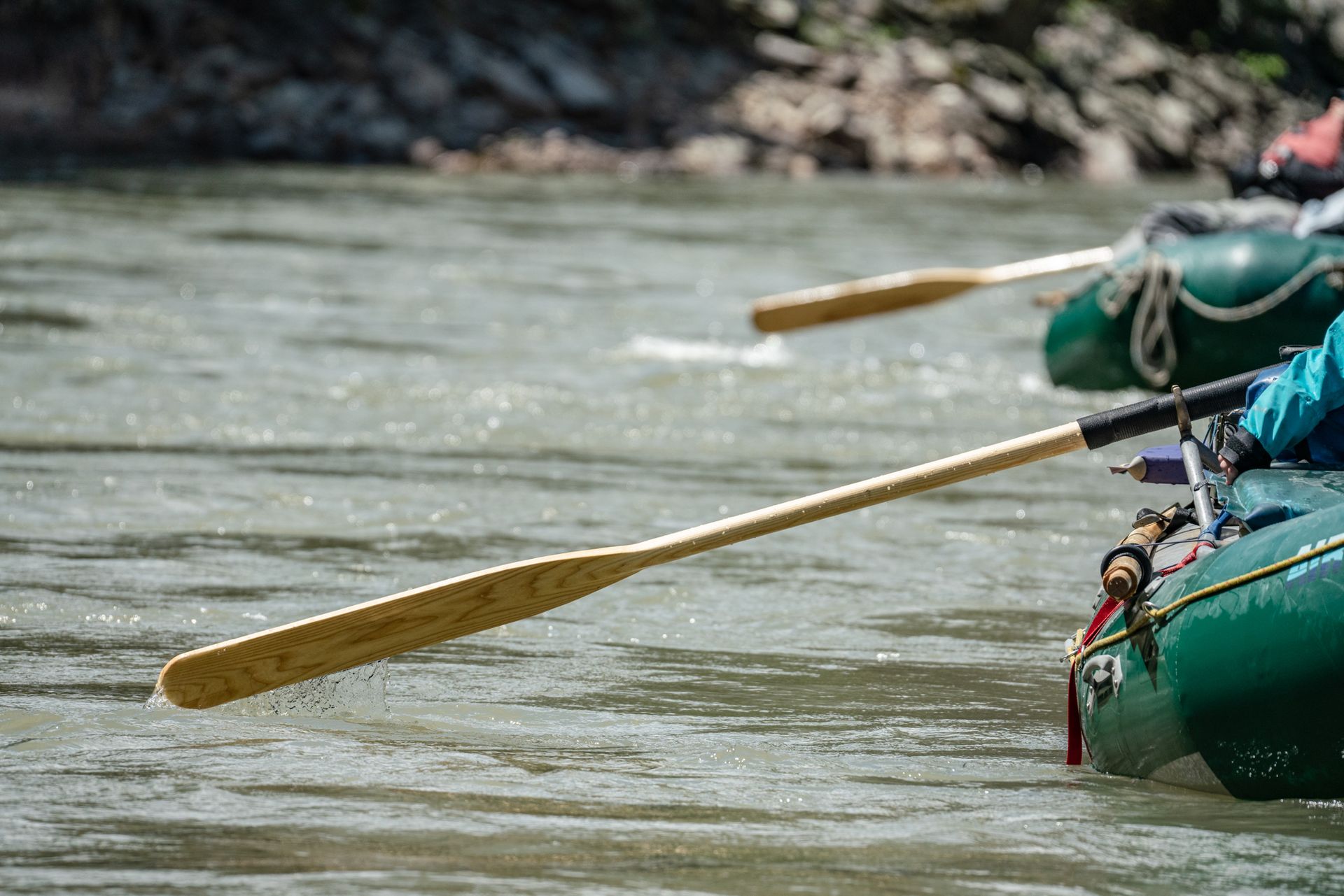 A group of people are rowing rafts down a river.